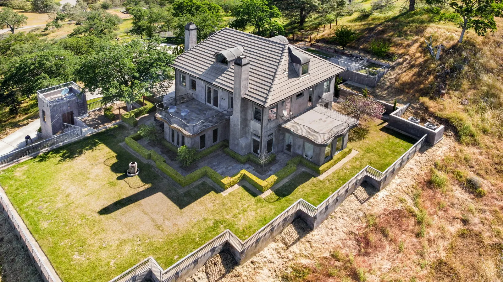 Aerial view of the villa, its lawn and terraces surrounded by oak hills