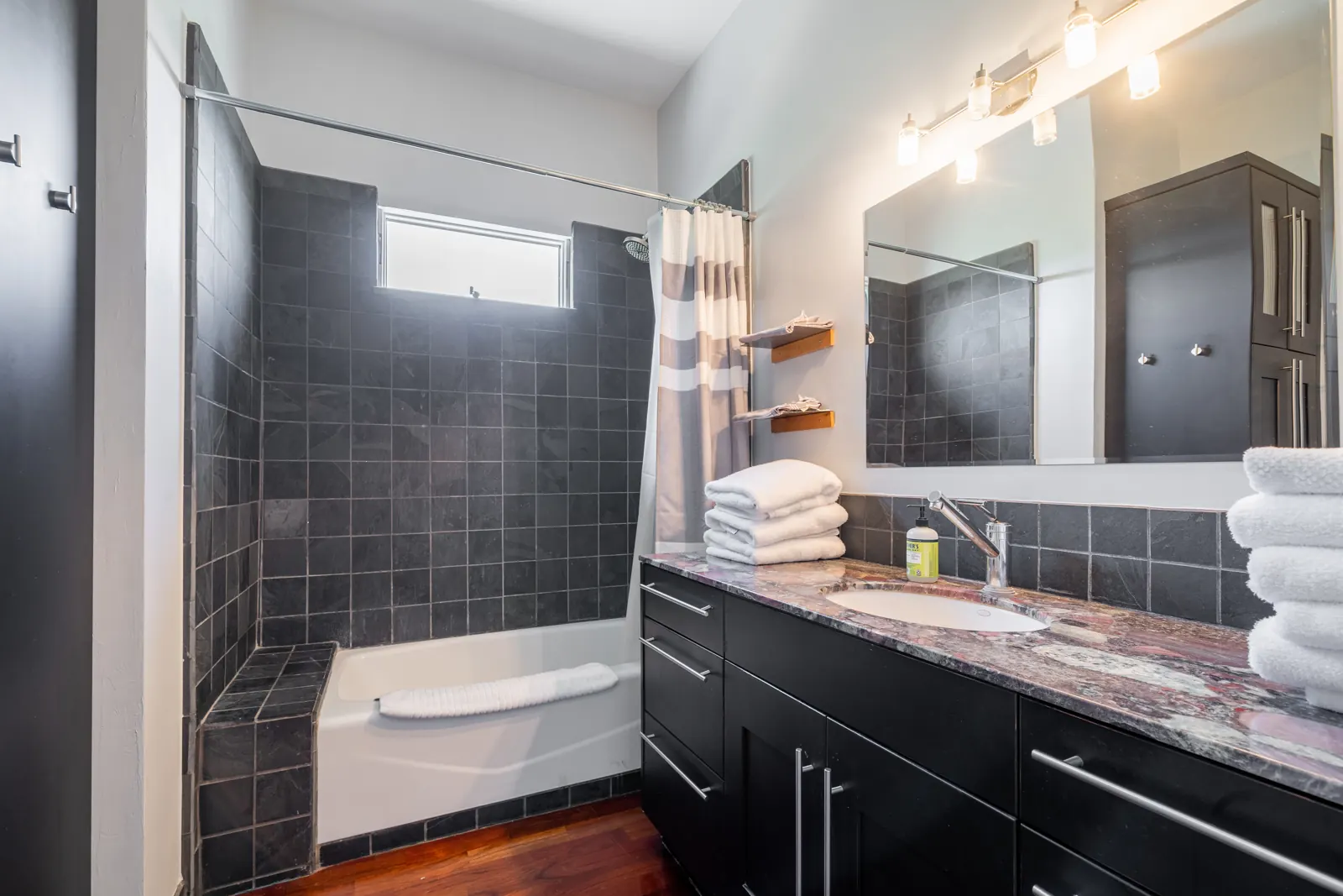 Bathroom with tiled tub and shower and a stone vanity