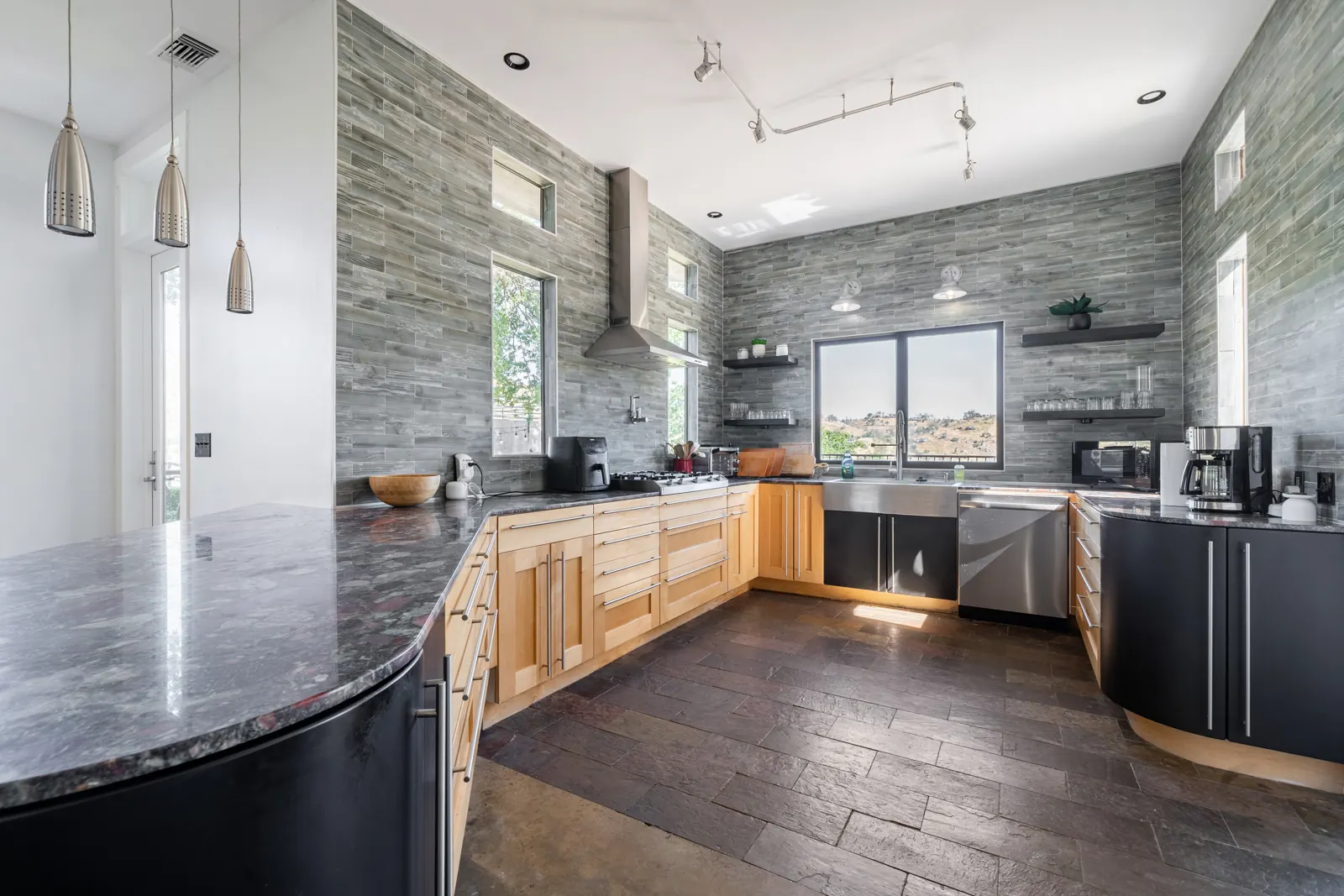 Chef's kitchen with stone accent wall and hillside window view