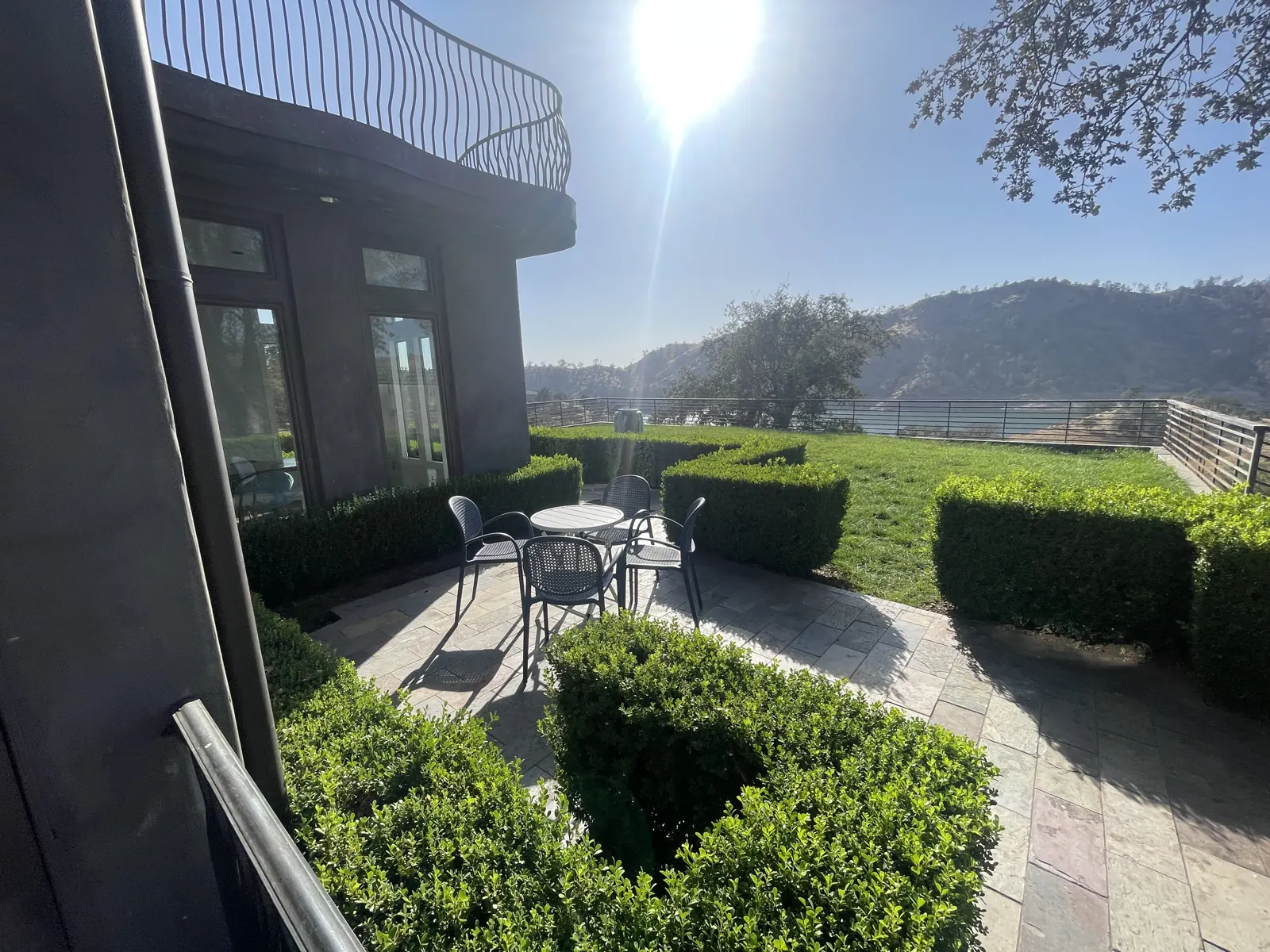 Hedge garden with a bistro table beside the house, opening onto the lawn and the hills