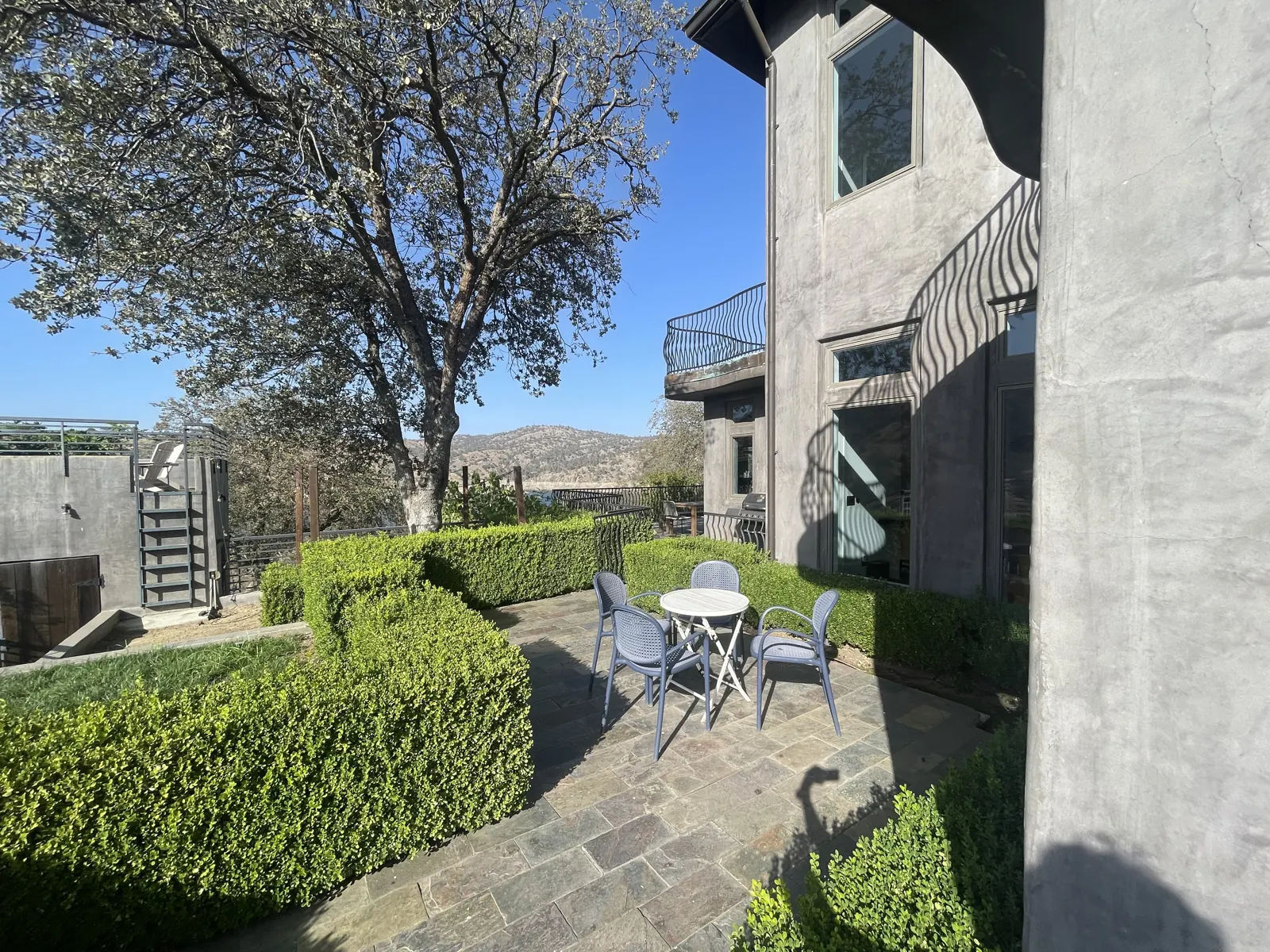 Hedge garden with white bistro tables beside the house