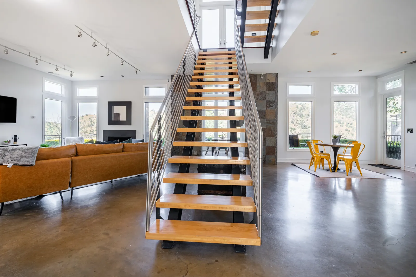 Open floating staircase in the great room, with the living area and breakfast nook on either side