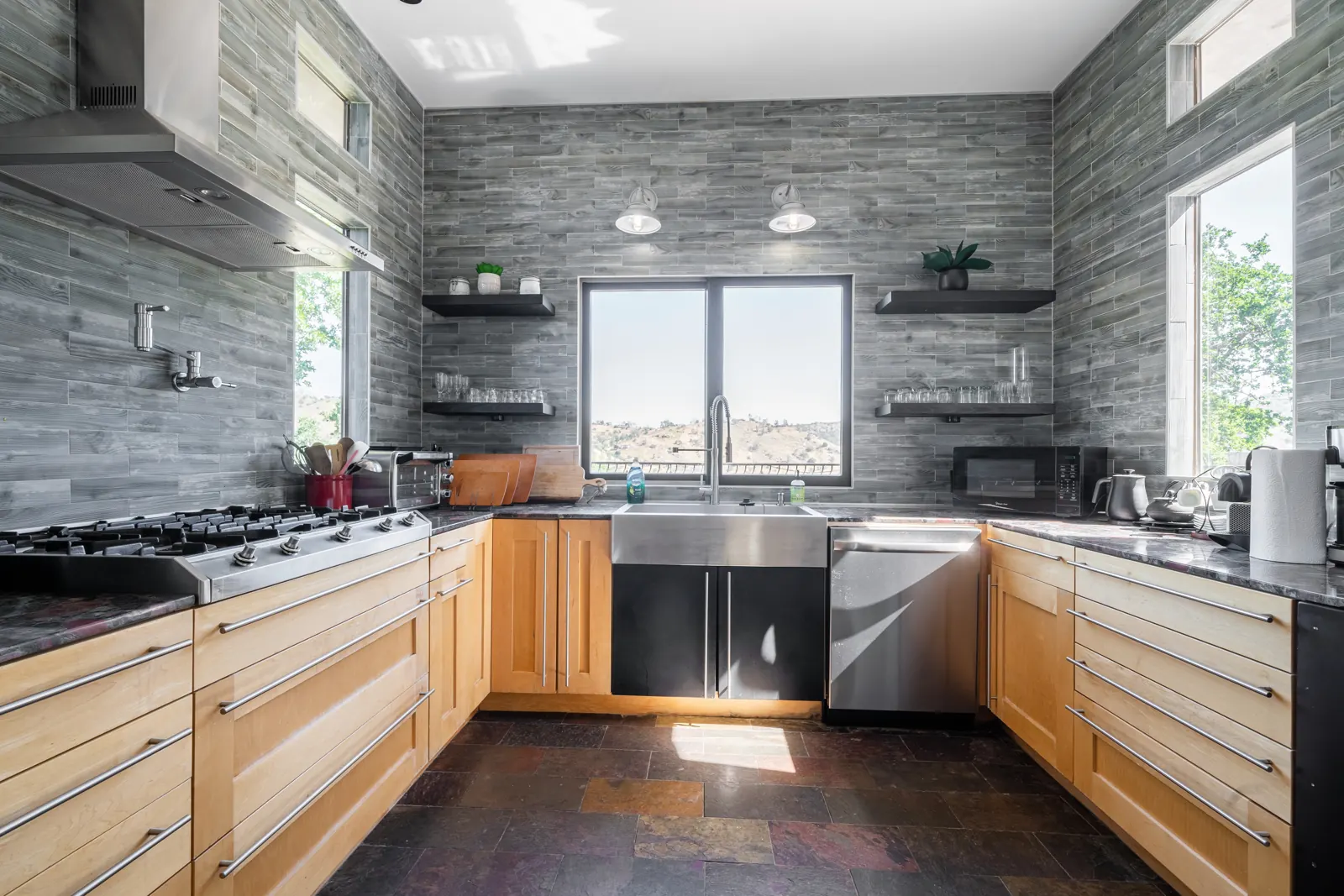 Kitchen with gas range, open shelving and a window over the sink