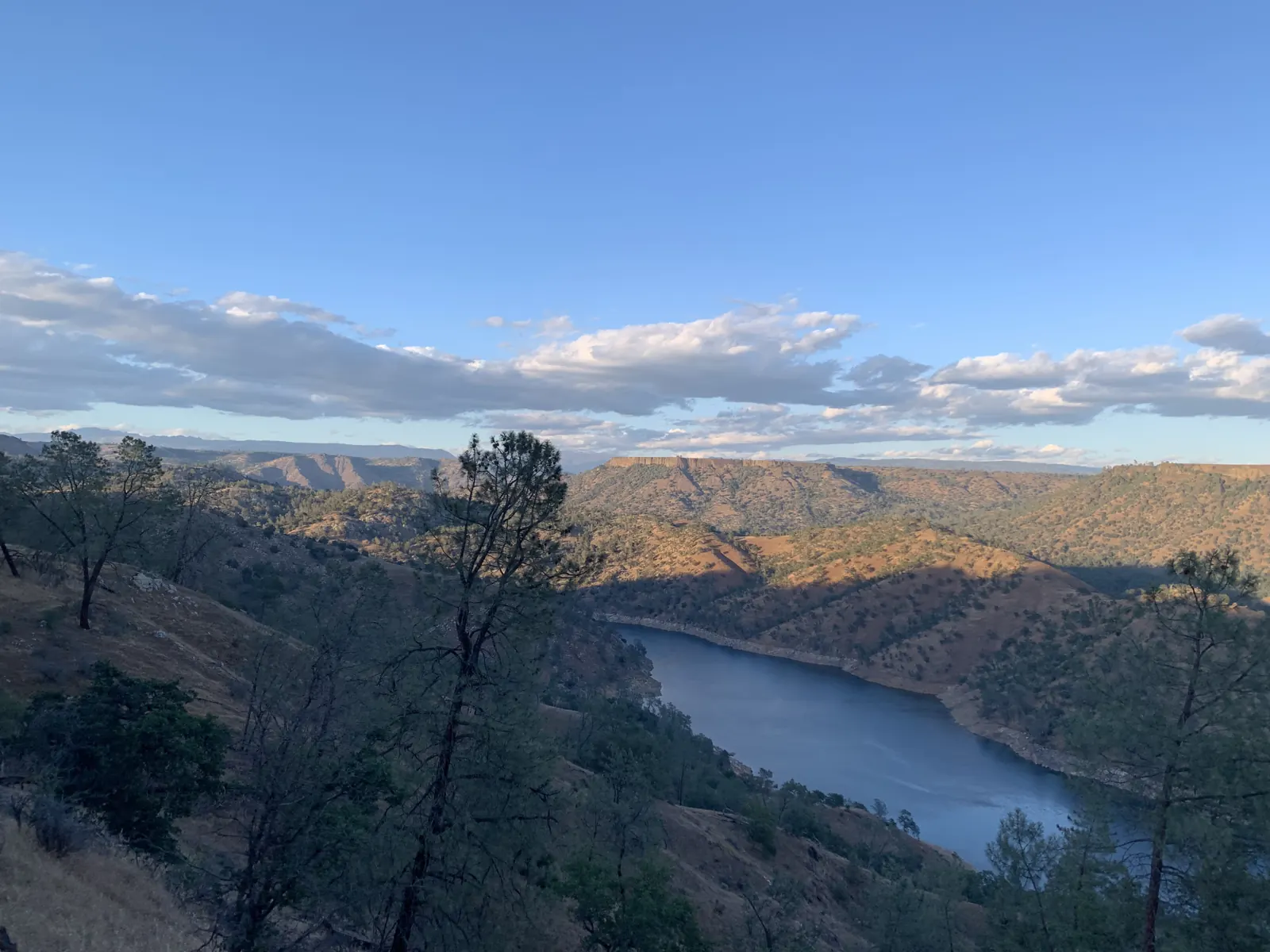 The lake curving through a wooded canyon, seen from a hillside trail