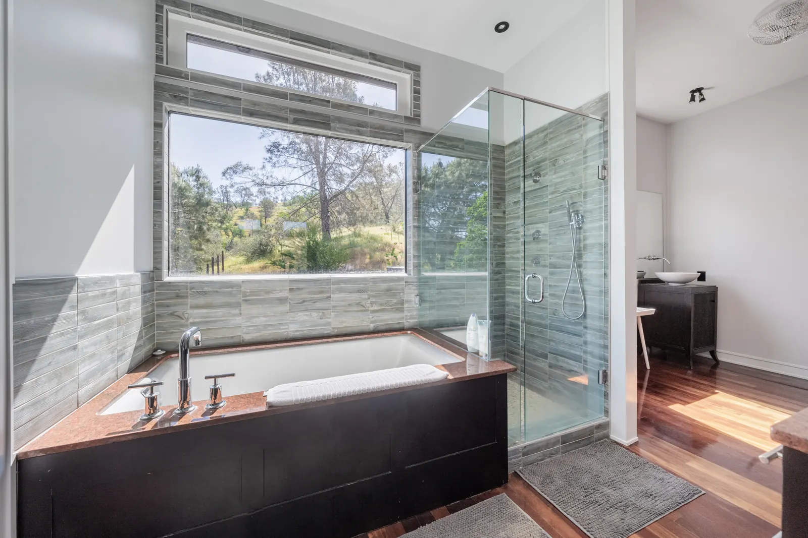 Primary bathroom with a soaking tub under a picture window and a glass walk-in shower
