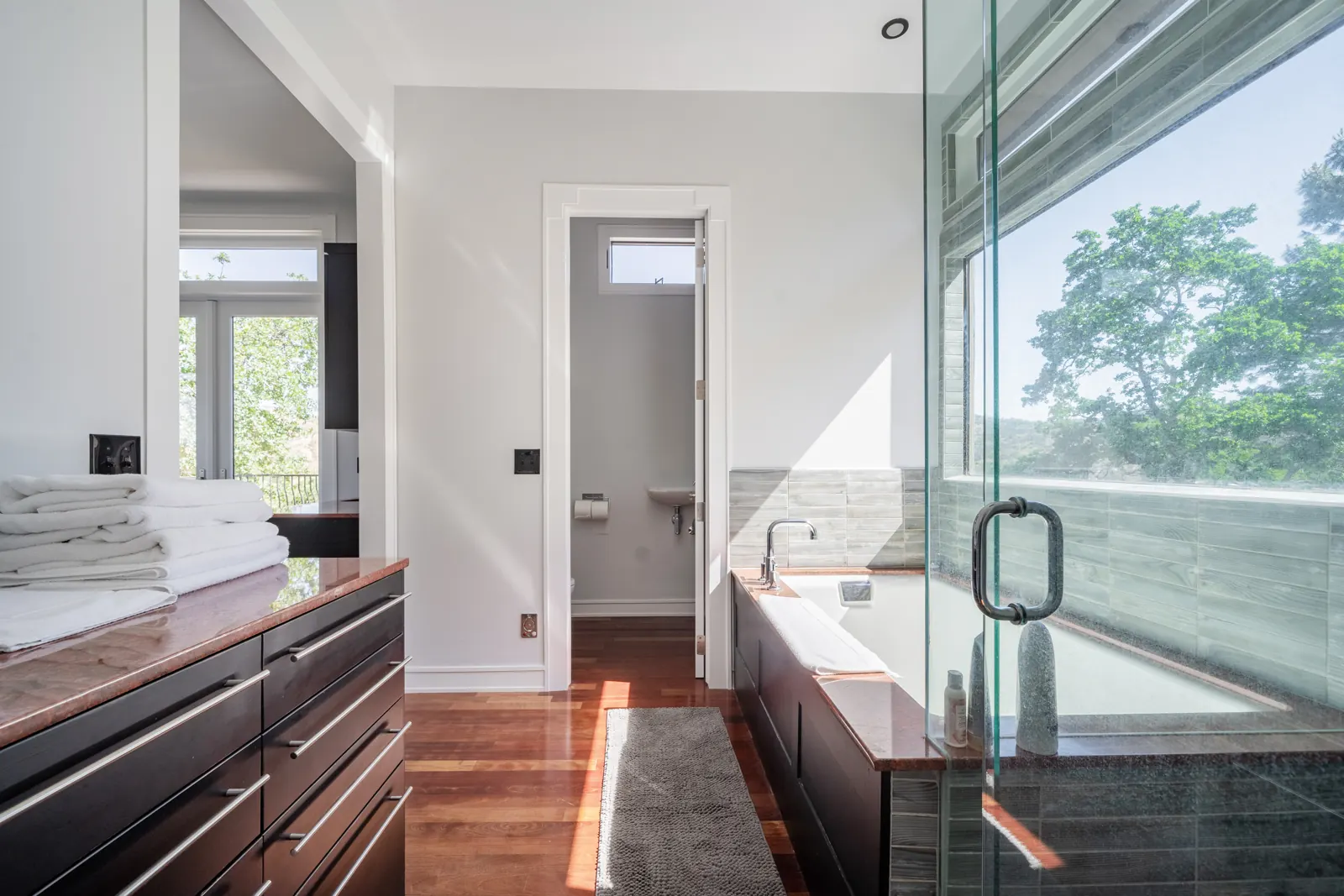 Primary bathroom with a long vanity, soaking tub, glass shower and a separate toilet room