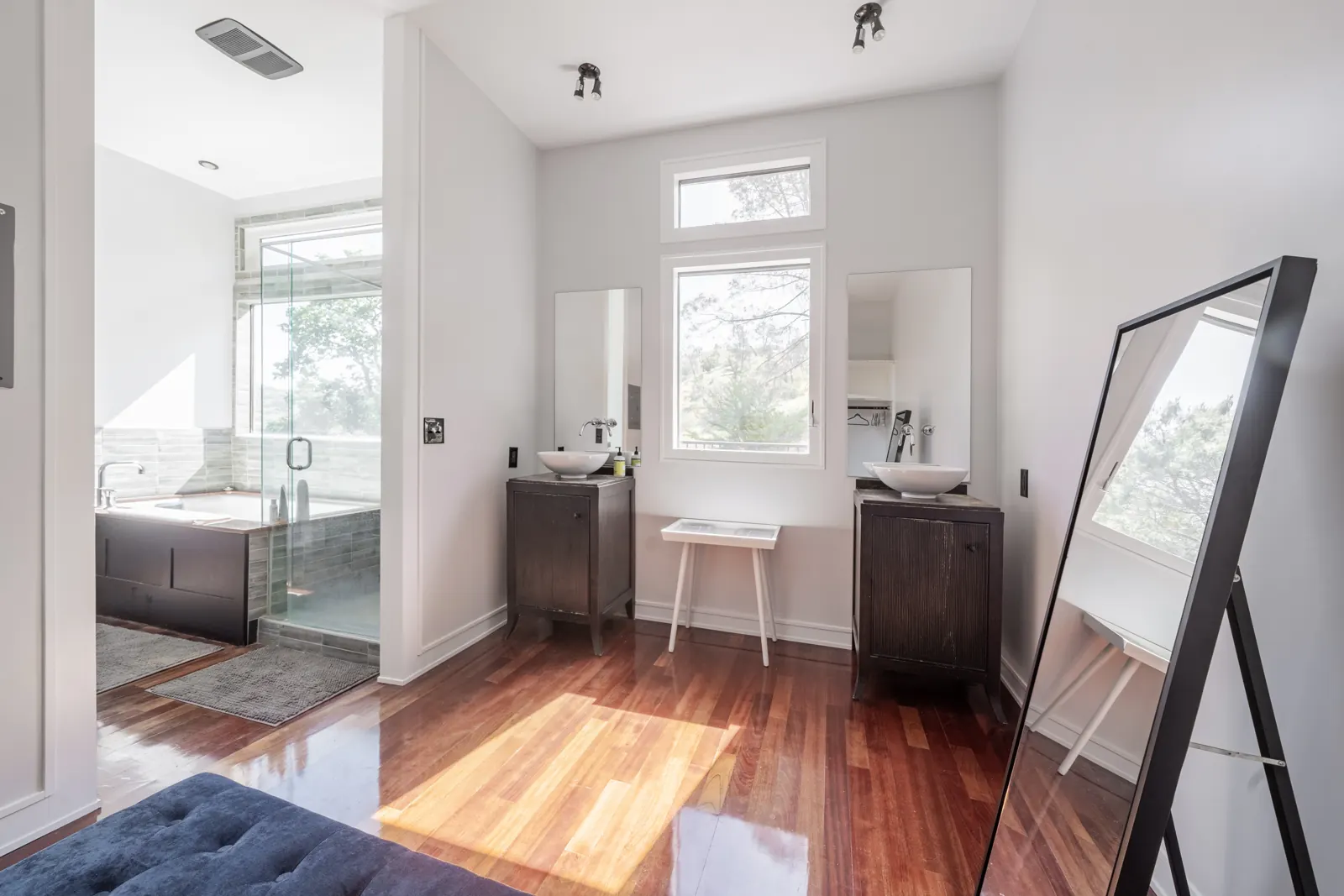 Primary suite dressing area with two vanities, a full-length mirror and views to the bathroom