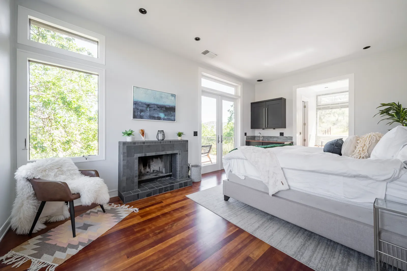 Primary suite with a king bed, tiled fireplace and French doors to the private balcony