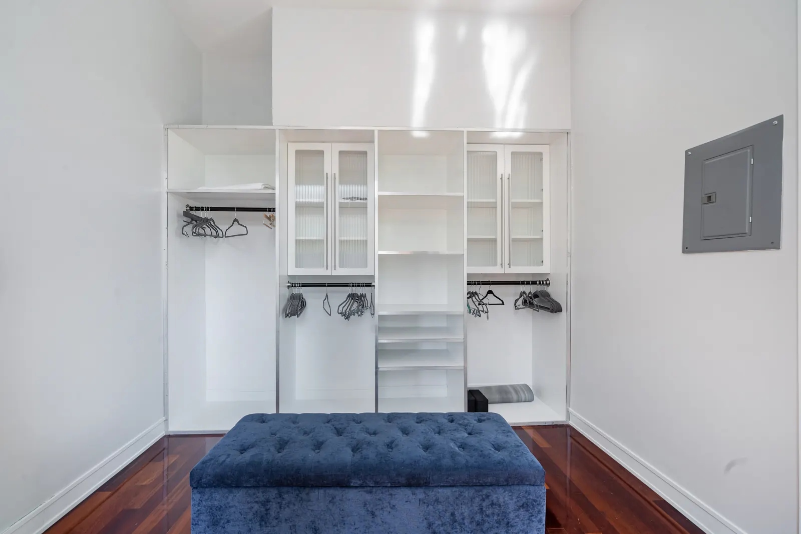 Walk-in closet in the primary suite with open shelving, hanging space and a bench