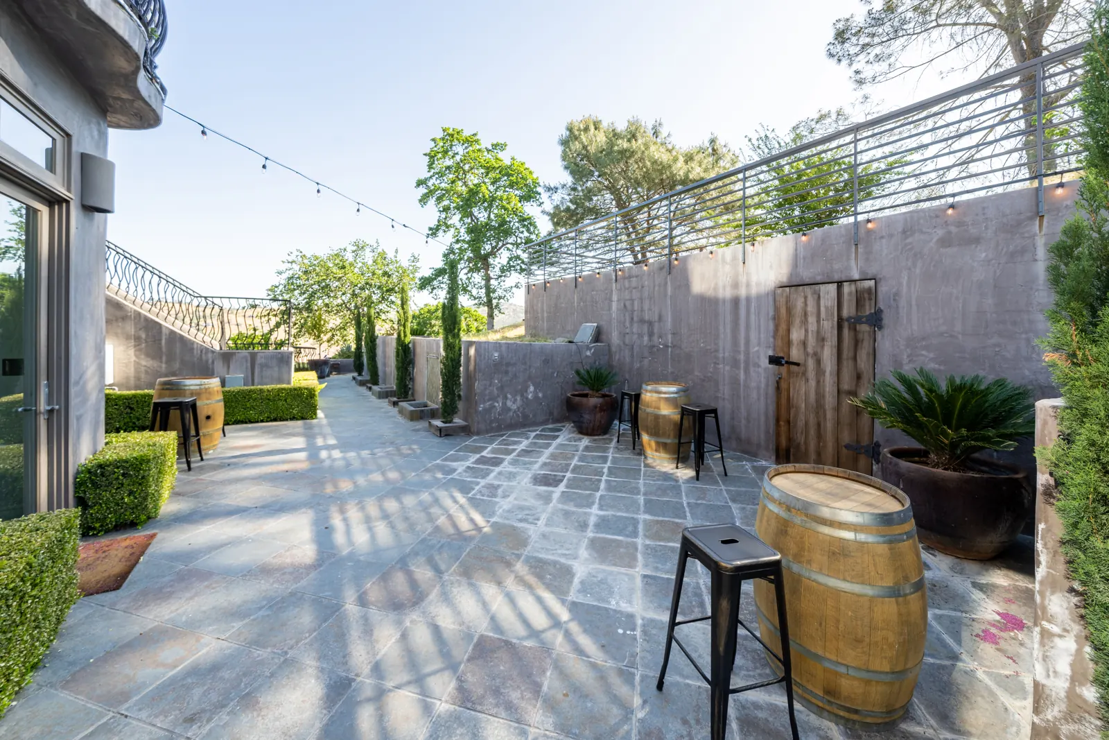 Paved courtyard by the wine cellar with barrel tables and string lights