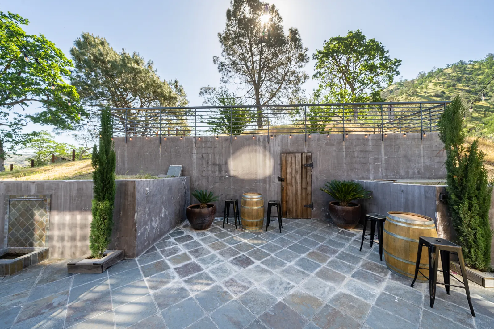 Courtyard by the wine cellar with its wooden door, barrels and cypress trees